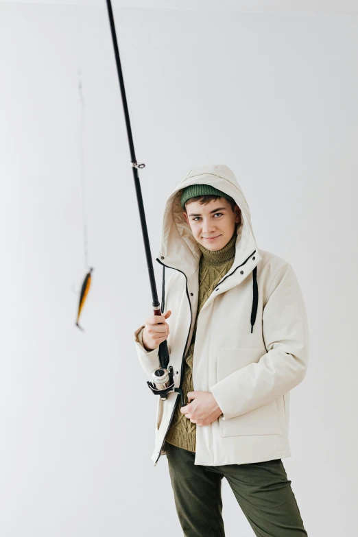 a man in a white jacket holding a fishing rod, an epic non - binary model, wearing hunter coat, wearing hoodie, white backround