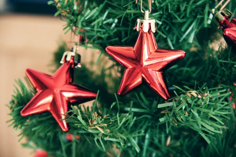 a red star ornament hanging from a christmas tree, pexels, hurufiyya, mini model, celebrity, enamel, 3 pm