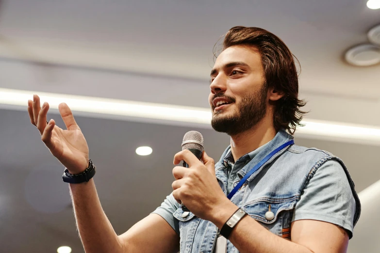 a man that is holding a microphone in his hand, shutterstock, academic art, young spanish man, 15081959 21121991 01012000 4k, instagram post, tech demo