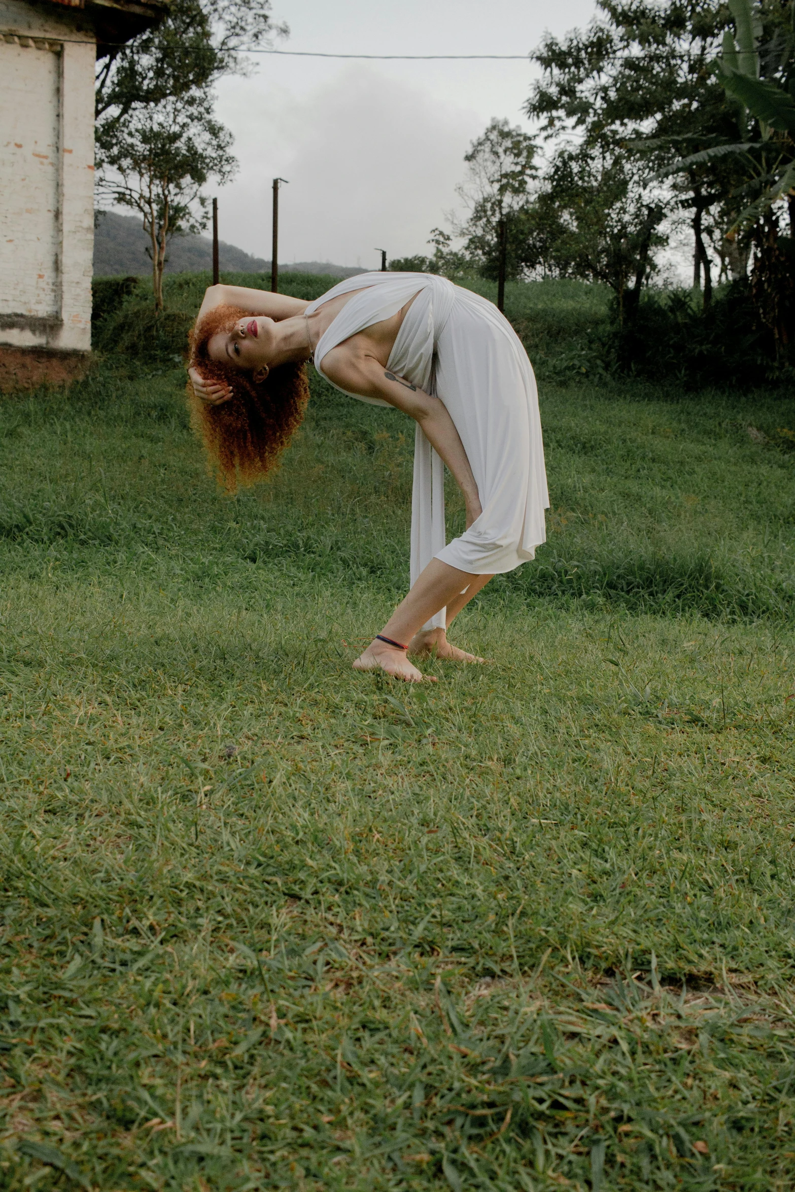 a woman doing a handstand in a field, an album cover, inspired by Elizabeth Polunin, renaissance, in sao paulo, in the yard, a redheaded young woman, round-cropped