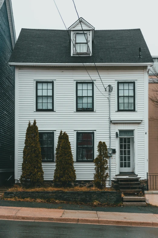 a white house sitting on the side of a road, pexels contest winner, black windows, new jersey, 1759, cozy environment