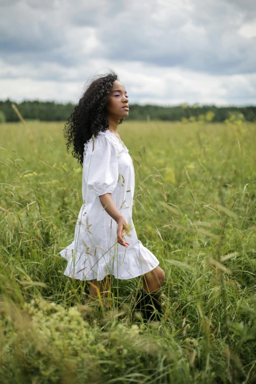 a woman walking through a field of tall grass, pexels contest winner, renaissance, natural hair, wearing a cute white dress, mixed-race woman, contemplating