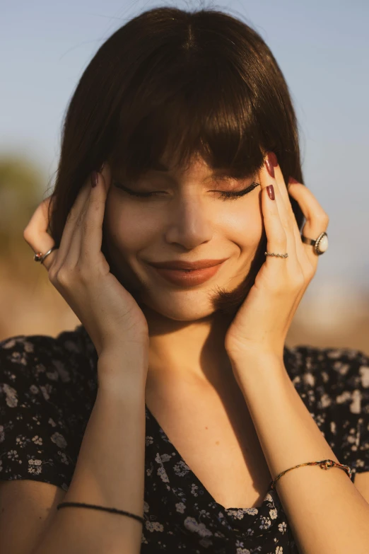 a woman holding her hands to her face, girl with dark brown hair, turning her head and smiling, feeling good, zoomed out