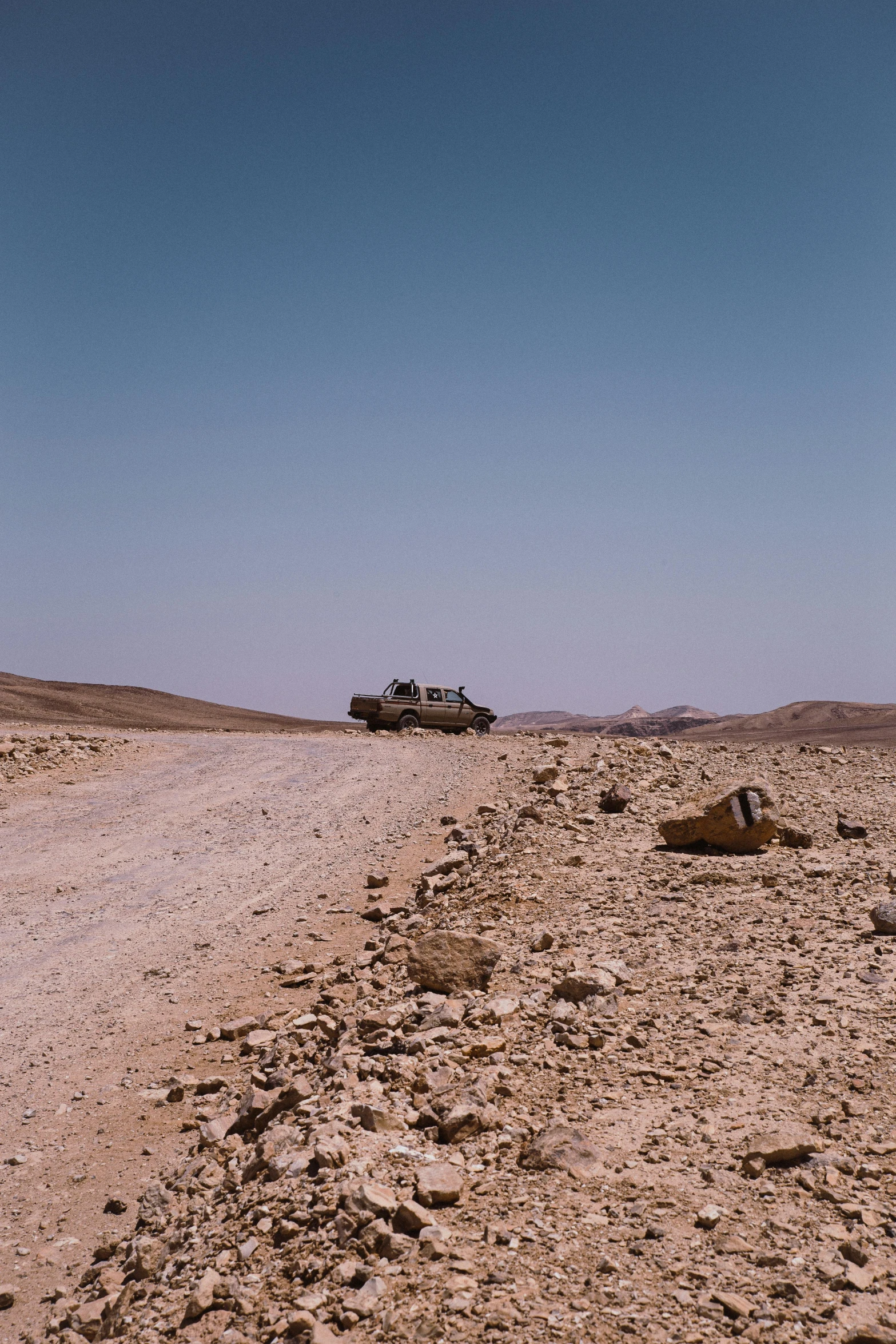 a truck driving down a dirt road in the desert, les nabis, in the distance is a rocky hill, ronen bekerman, tank, photo taken on fujifilm superia