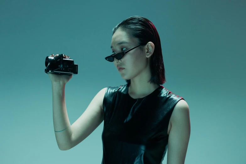 a woman in a leather dress holding a camera, inspired by Fei Danxu, unsplash, bauhaus, futuristic ar glasses, dilraba dilmurat, vhs colour photography, press shot