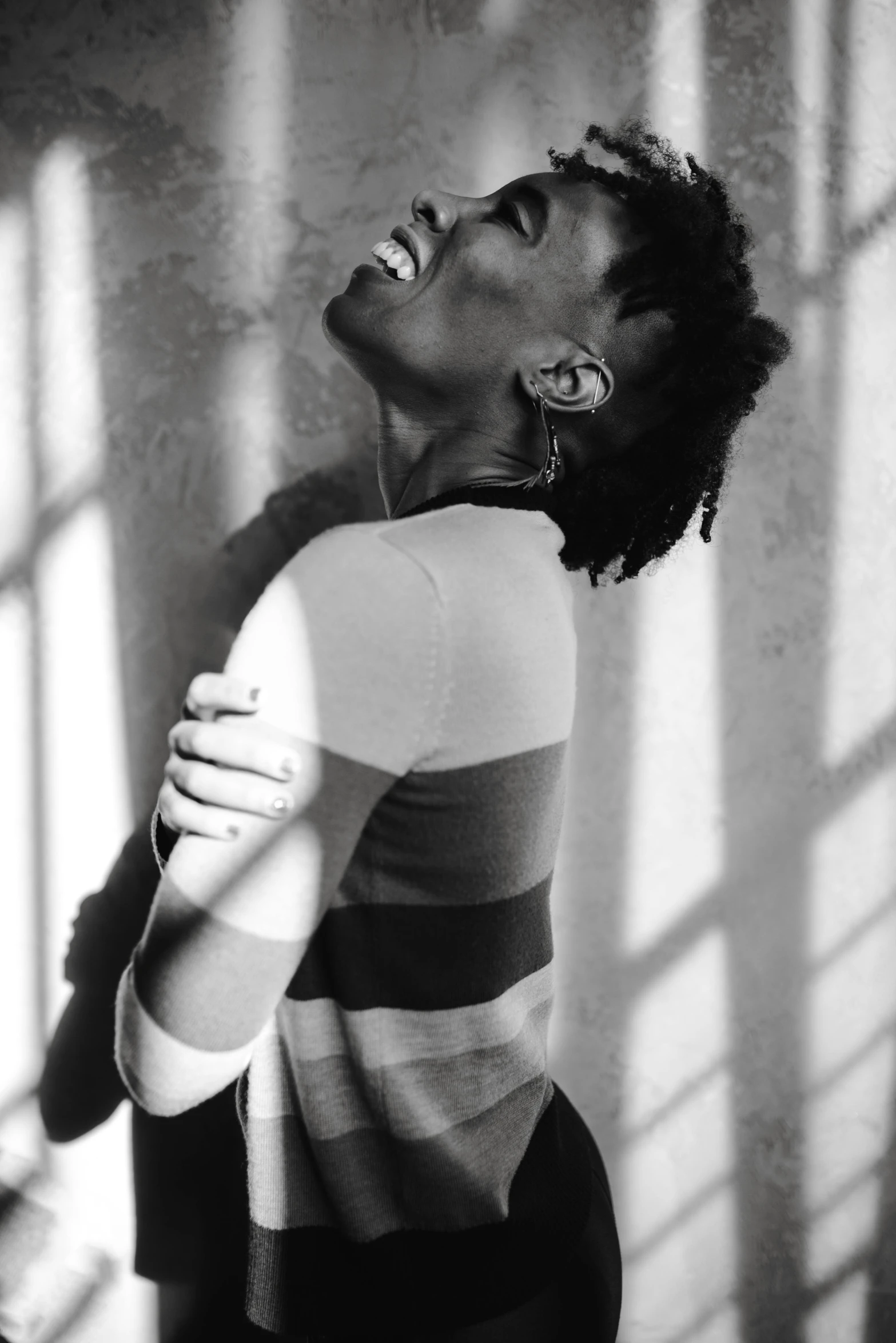 a black and white photo of a woman laughing, pexels contest winner, black arts movement, stood in a cell, willow smith young, sun beam, embracing