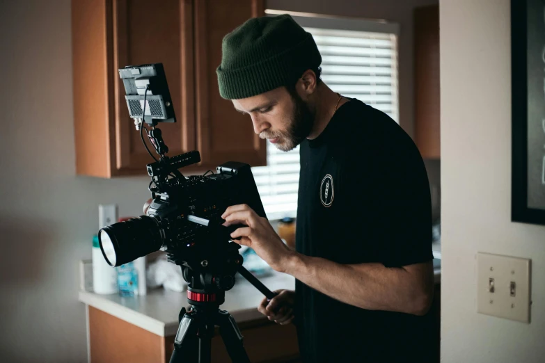 a man standing next to a camera on a tripod, a portrait, pexels contest winner, video art, cooke anamorphic / i lenses, cinematic headshot portrait, vsco film grain, subtitles