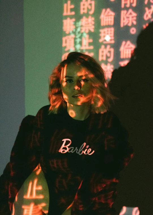 a woman standing in front of a neon sign, inspired by Elsa Bleda, trending on unsplash, wearing a black sweater, portrait of barbie doll, japanese streetwear, grainy footage