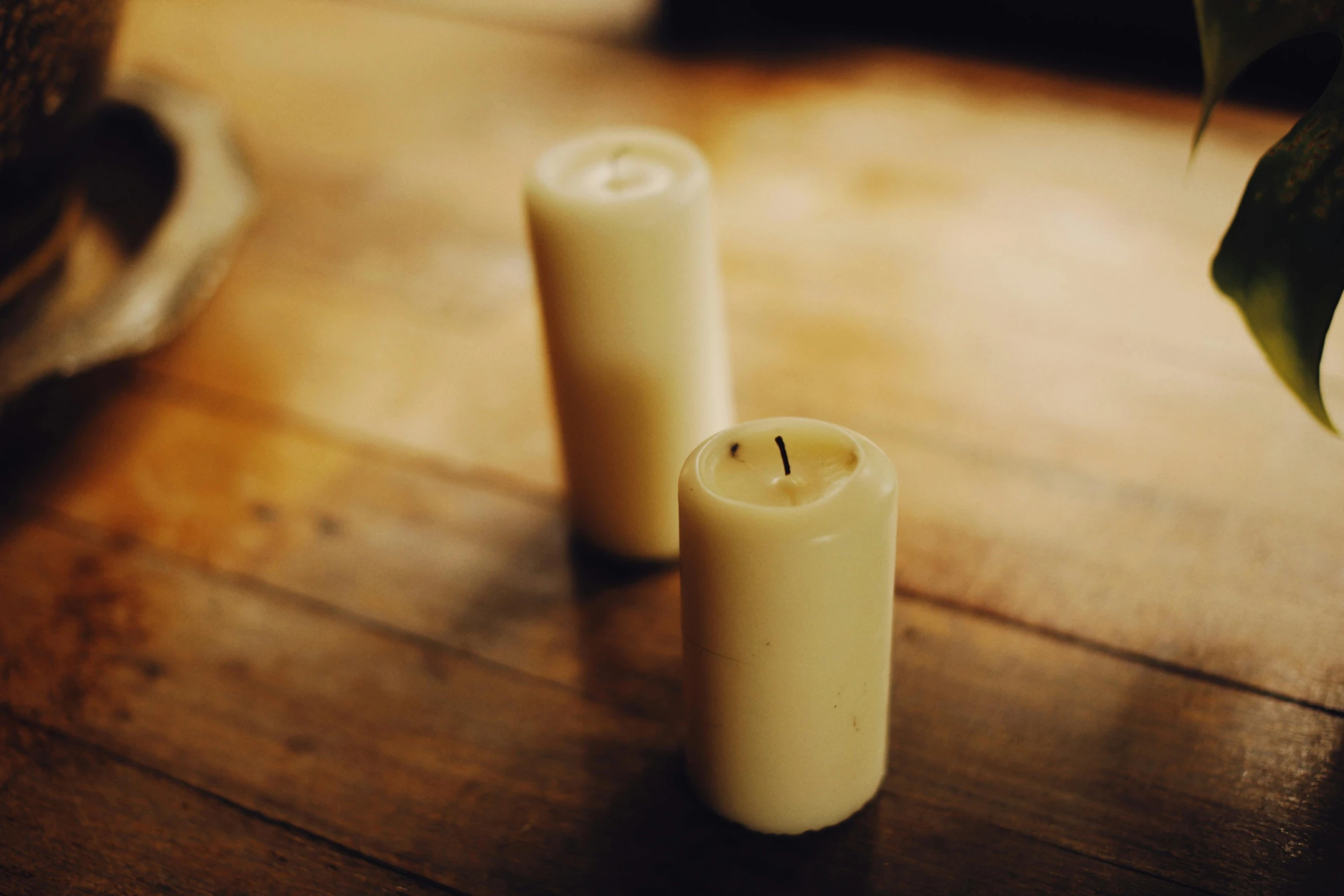 two white candles sitting on top of a wooden table, unsplash, faded worn, o'neill cylinder, multiple stories, indoor picture