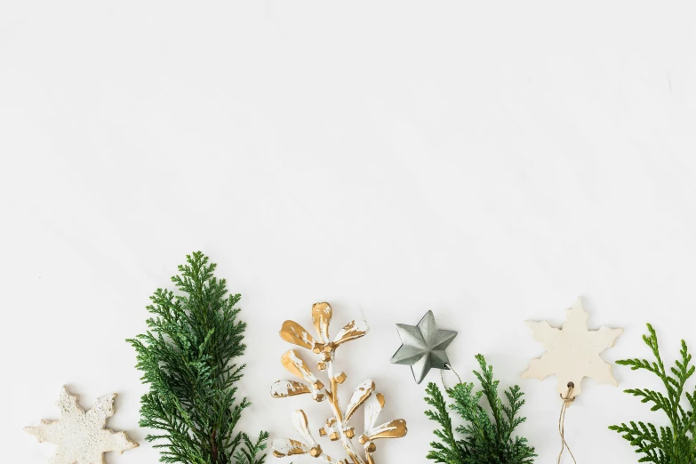 a group of christmas decorations sitting on top of a table, trending on pexels, minimalism, evergreen branches, background image, tiny stars, white flowers on the floor