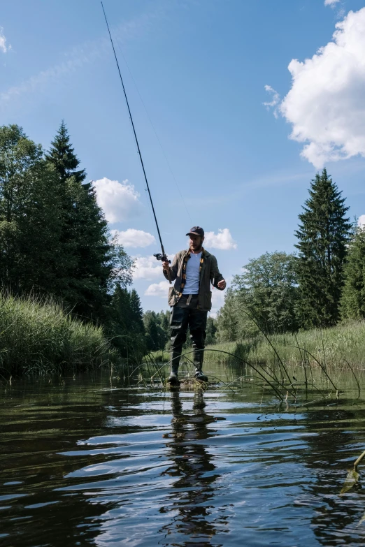 a man that is standing in the water with a fish, swedish countryside, with trees and rivers, riding, wearing a fisher 🧥