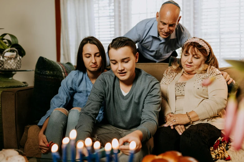 a group of people sitting around a birthday cake, holding a candle holder, eytan zana, mourning family, 15081959 21121991 01012000 4k