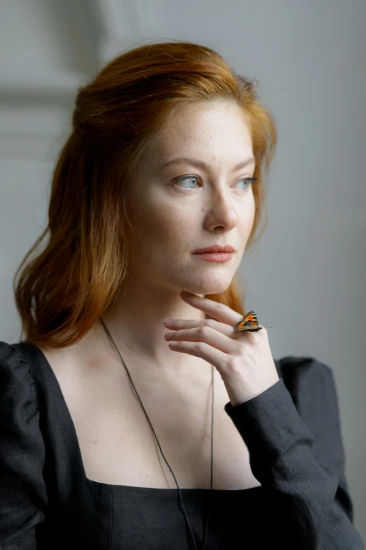 a woman with red hair wearing a black dress, looking away from camera, woman's face looking off camera, sienna, promo image