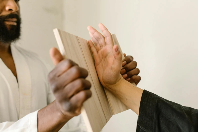 a man standing next to a woman holding a book, pexels contest winner, reaching out to each other, holding a wood piece, panel of black, varying ethnicities