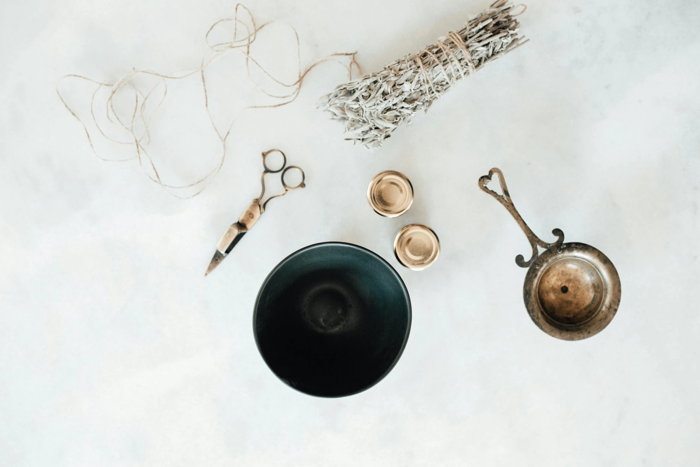 a black bowl sitting on top of a table next to a pair of scissors, a still life, trending on pexels, incense, made of polished broze, set against a white background, image apothecary