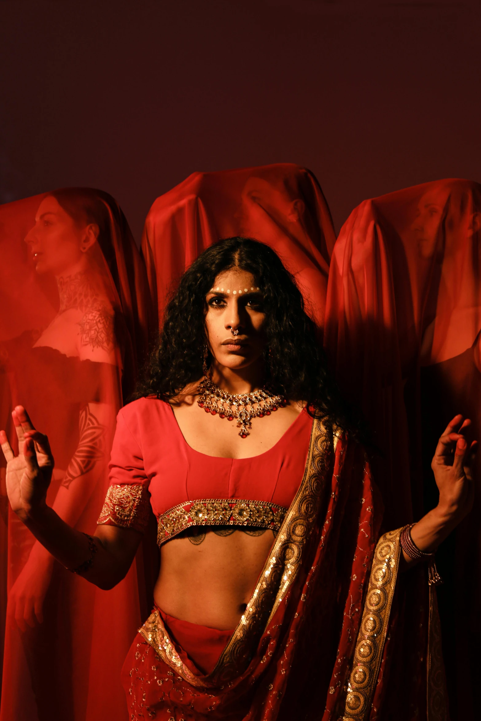 a woman in a red sari posing for a picture, an album cover, transgressive art, trans rights, [ theatrical ], dimly lit scene, saint womans