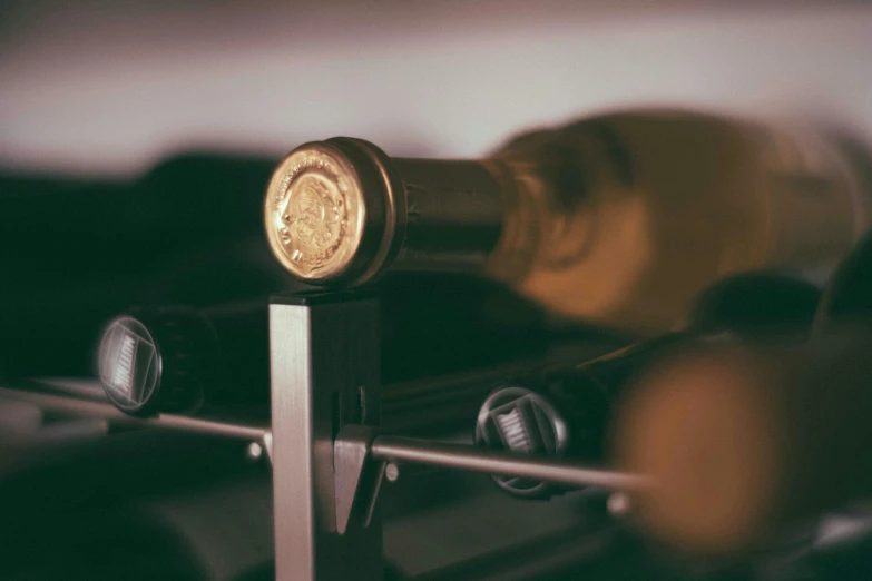 a close up of a wine bottle on a rack, an engraving, pexels contest winner, gold and silver and brass, view from the side, clubs, thumbnail