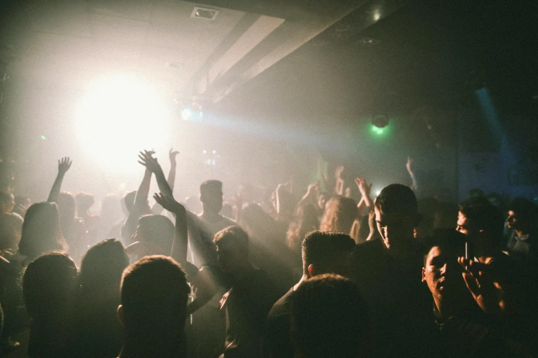 a crowd of people at a concert with their hands in the air, by Nick Fudge, smokey room, dancefloor, sunfaded, dimly lit room
