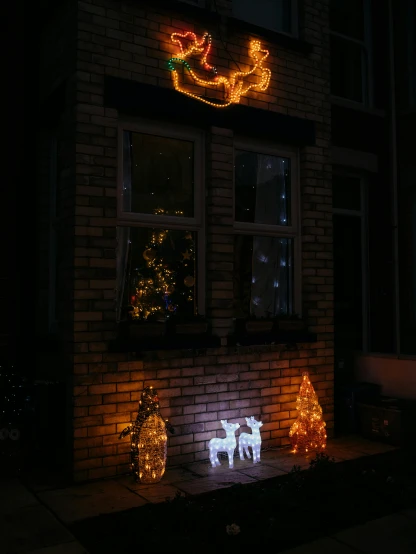 a lighted reindeer and sleigh in front of a house, by Adam Rex, ambient amber light, atmospheric lighting - n 9, ultra detailed wire decoration, low quality photo