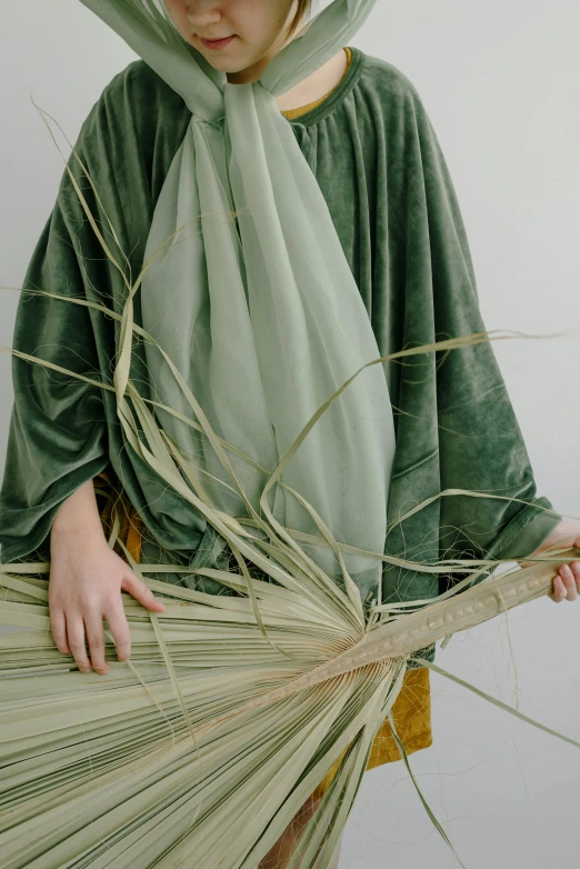 a woman in a green costume holding a fan, an album cover, inspired by Marià Fortuny, unsplash, wearing hay coat, drapery, natural materials, ignant