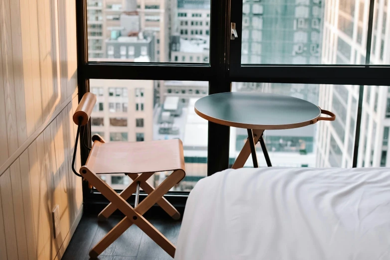 a bed sitting in a bedroom next to a window, by Carey Morris, trending on unsplash, cafe tables, new york city, stools, in style of norman foster