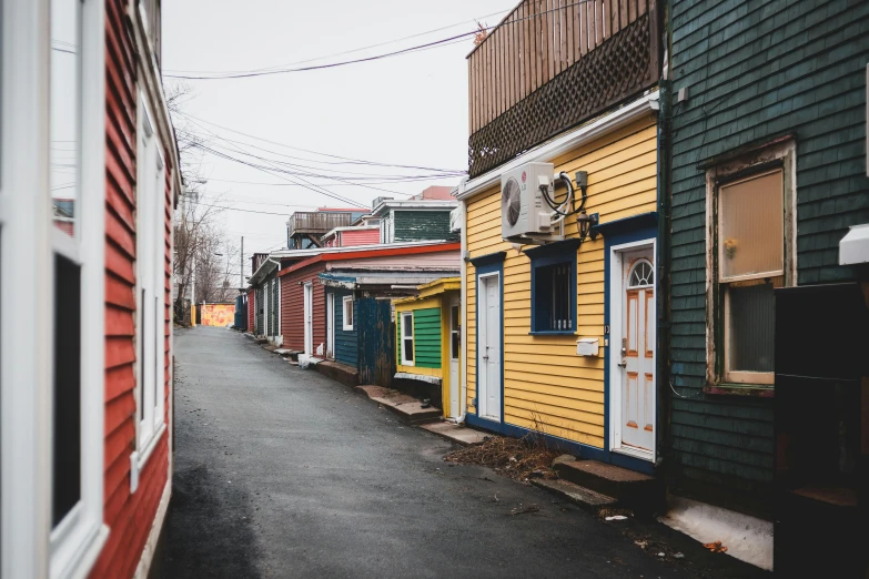 a street lined with colorful buildings next to each other, by Carey Morris, pexels contest winner, shanty townships, grey, notan, vibrant but dreary gold