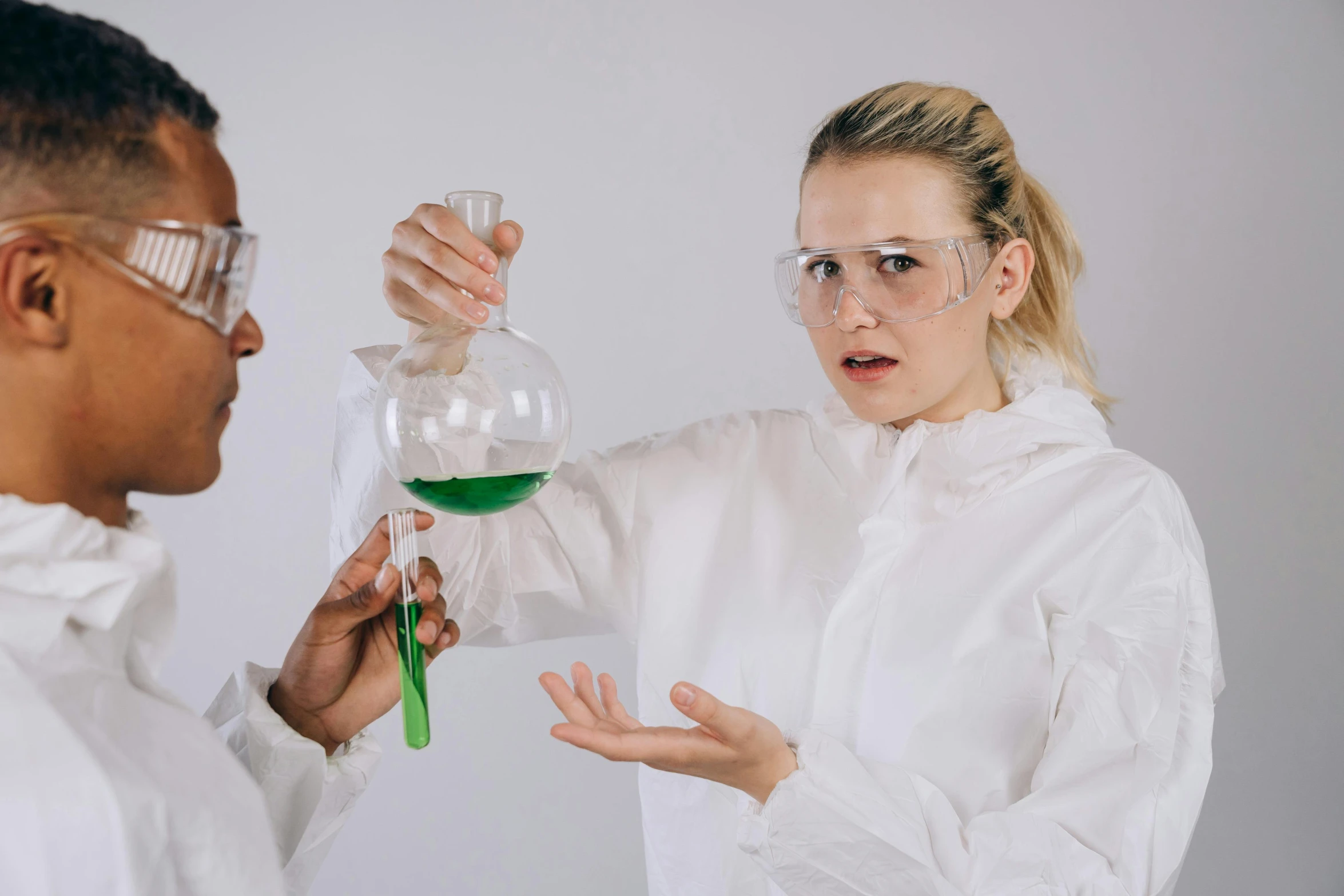 a man and a woman in lab coats holding flasks, trending on pexels, analytical art, white shirt and green skirt, gif, experimenting, dissection of funny