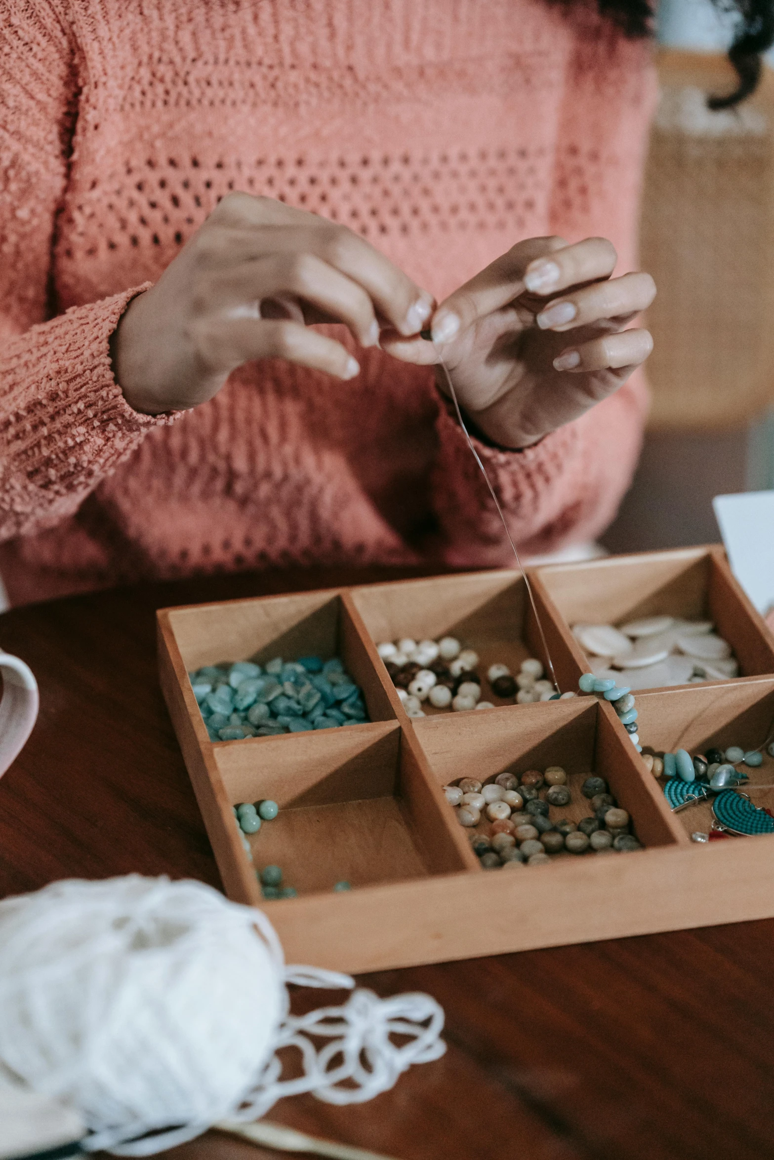 a woman sitting at a table with a box of beads, inspired by Elsa Bleda, trending on pexels, buttons, teal paper, mineral collections, product introduction photo