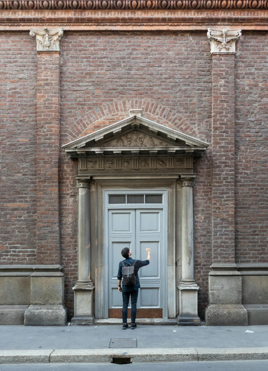 a man that is standing in front of a door, inspired by Pieter de Hooch, pexels contest winner, brick building, at a museum, in full growth from the back, high resolution photo