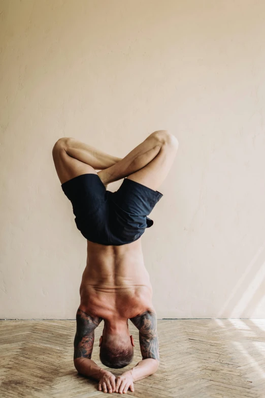 a man doing a handstand in a room, a tattoo, trending on pexels, cropped red yoga short, face neck shoulders, manly, brown