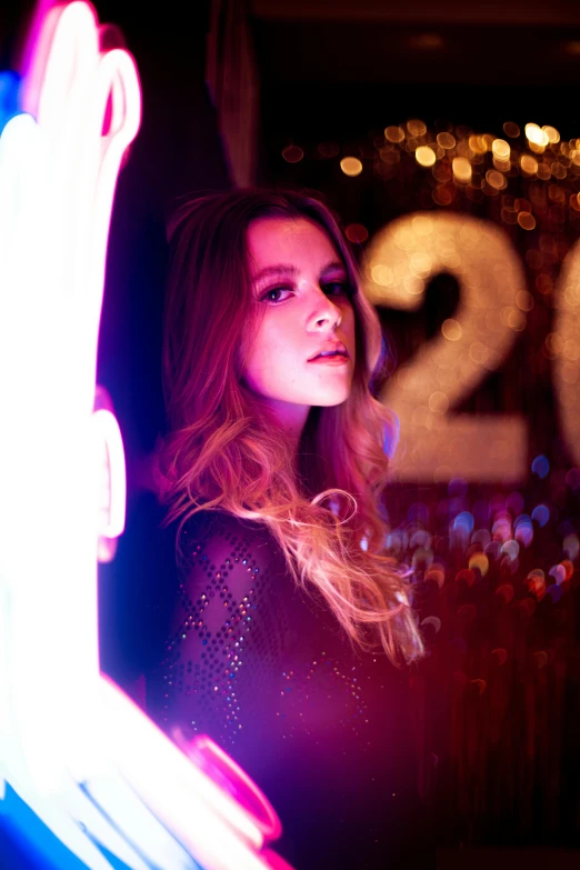 a woman standing in front of a neon sign, by Julia Pishtar, natalie dormer, new years eve, profile image, concert photo