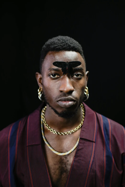 a man standing in front of a black background, an album cover, inspired by Godfrey Blow, trending on pexels, afrofuturism, big eyebrows, playboi carti portrait, jeweled ornament over forehead, rankin