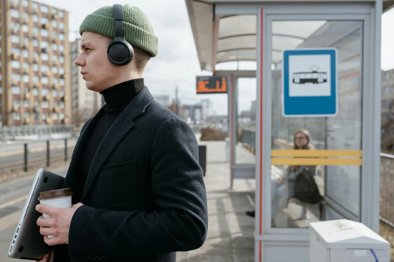 a man standing at a bus stop with headphones on, trending on pexels, bauhaus, nordic, tv still, headphones on head, subway station
