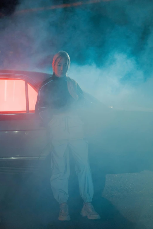 a man standing next to a car in the fog, an album cover, inspired by Elsa Bleda, pexels contest winner, conceptual art, neon operator margot robbie, white thick smoke, ( ( theatrical ) ), horror lighting