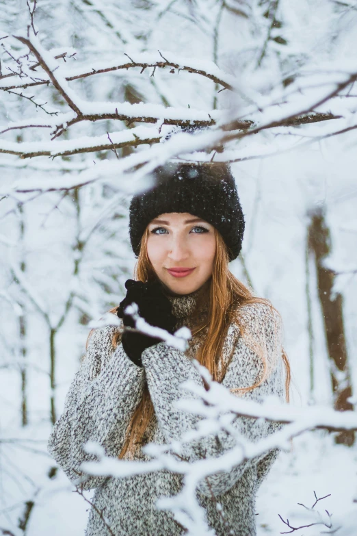 a woman standing next to a tree covered in snow, a portrait, trending on pexels, renaissance, better known as amouranth, beanie, avatar image, mittens