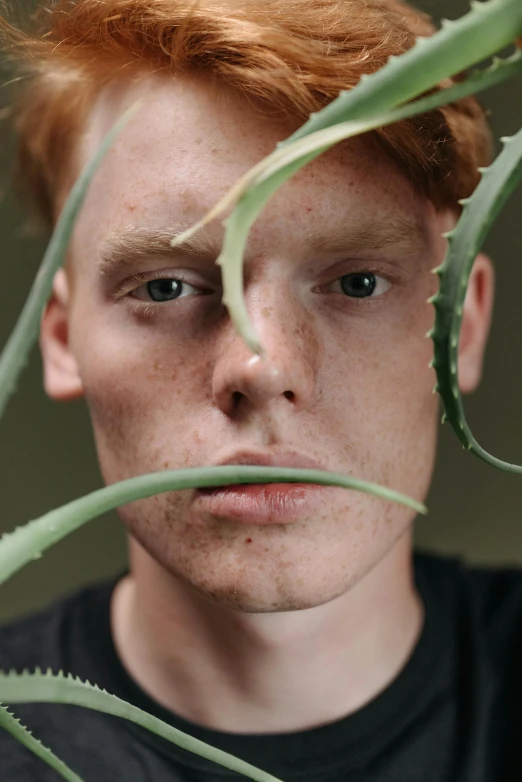 a close up of a person with a plant in front of him, ginger hair with freckles, non binary model, spiky, ignant