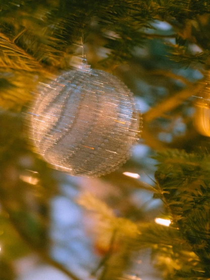 a silver ornament hanging from a christmas tree, by Adam Marczyński, pexels, translucent sphere, soft light - n 9, multiple stories, full frame image