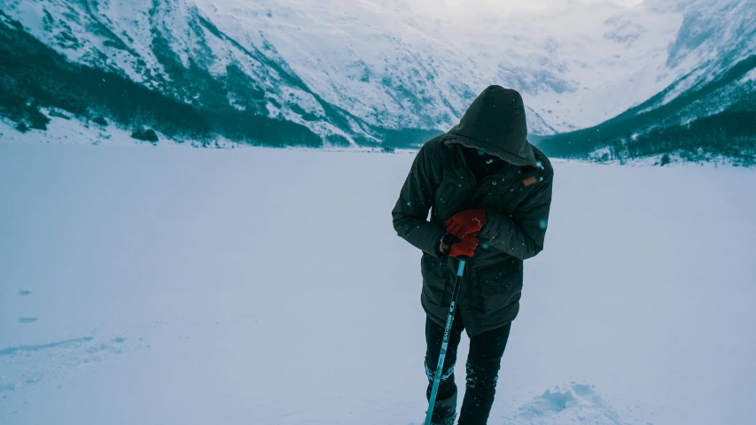 a man riding skis down a snow covered slope, pexels contest winner, visual art, obscured hooded person walking, near a lake, holding a crowbar, wearing hunter coat