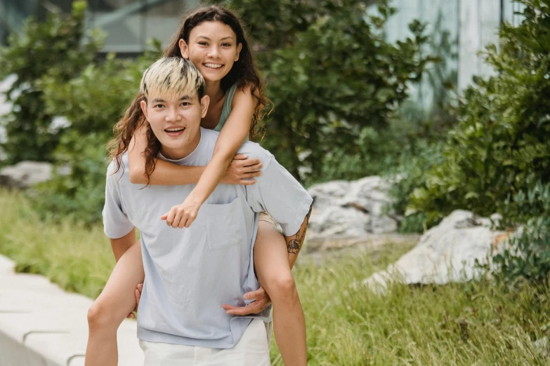 a man riding on the back of a woman on a skateboard, pexels contest winner, happening, tan skin a tee shirt and shorts, yee chong silverfox, on a green hill, young asian woman
