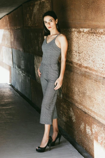a woman in a dress leaning against a wall, inspired by Ruth Jên, unsplash, wearing prison jumpsuit, square, dressed in a gray, manila