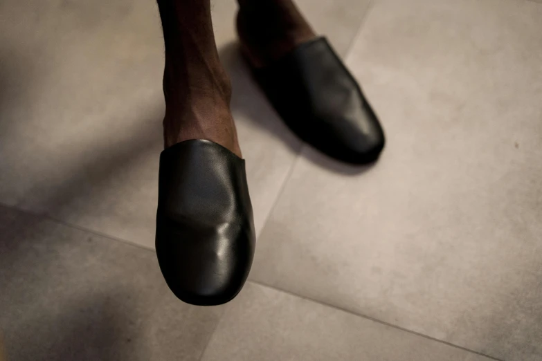 a close up of a person wearing black shoes, inspired by Théodule Ribot, matte finish, slippers, medium format. soft light, leather padding