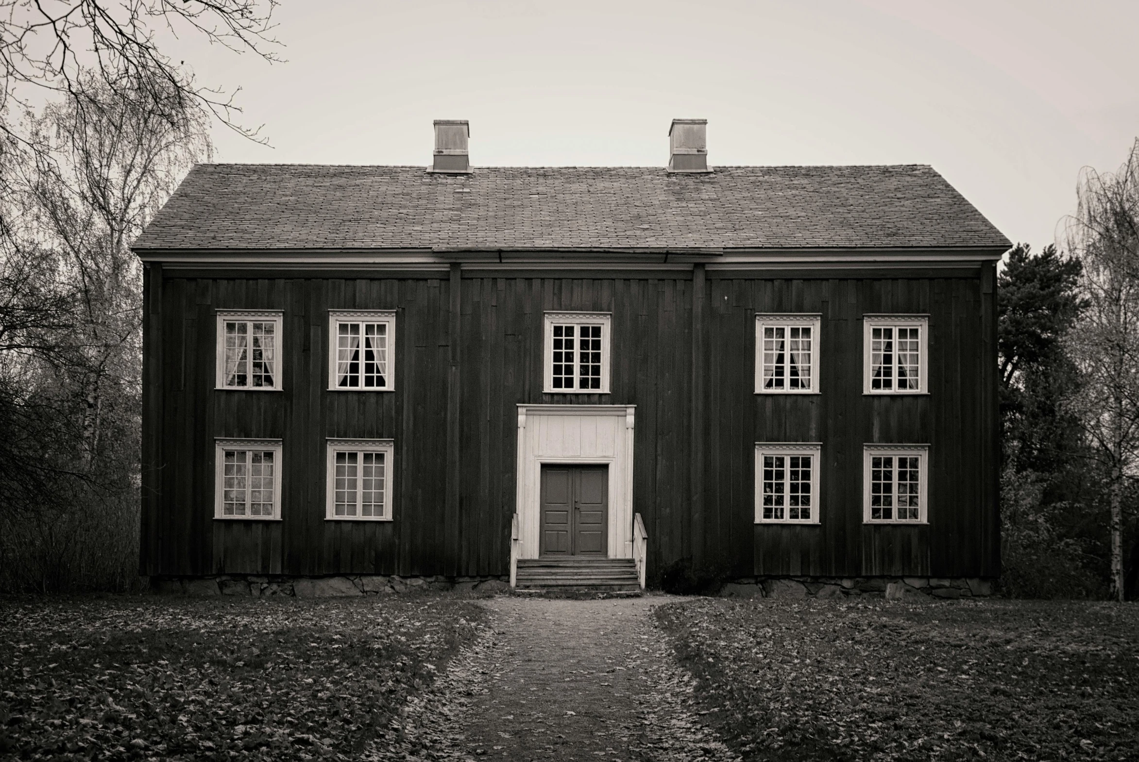 a black and white photo of a house, by Jesper Myrfors, pexels contest winner, colonial style, brown, halloween, frontal picture