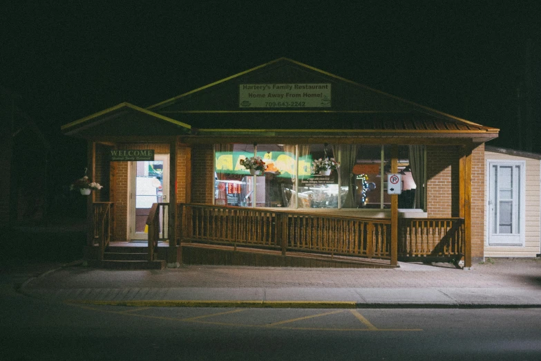 a man standing in front of a building at night, by Andrew Stevovich, convenience store, fancy restaurant, small town, lachlan bailey