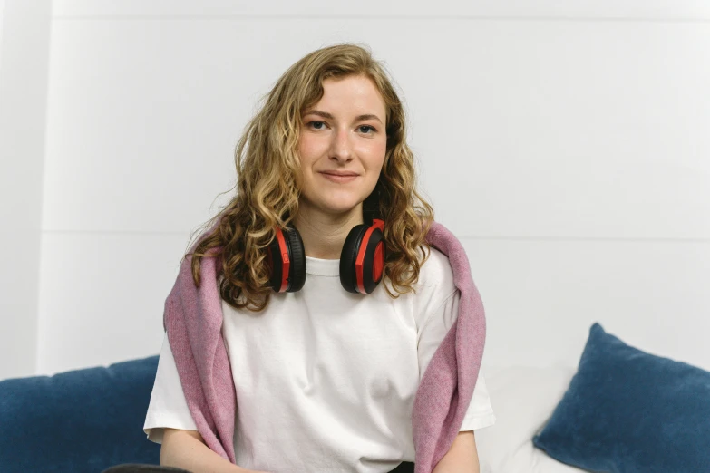 a woman sitting on a couch with headphones on, sydney hanson, profile image, portrait photo, slightly red