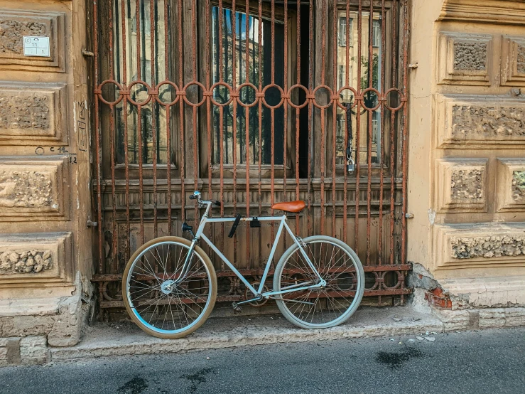 a bicycle leaning against a gate in front of a building, a picture, pexels contest winner, renaissance, ivory and copper, square, set photo