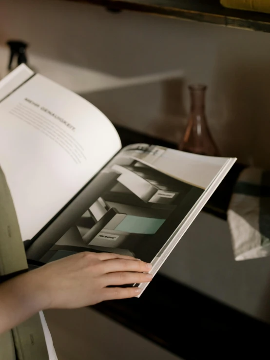 a close up of a person holding a book, a colorized photo, inspired by Richard Hamilton, unsplash, printed page, ignant, tonalism style, high angle