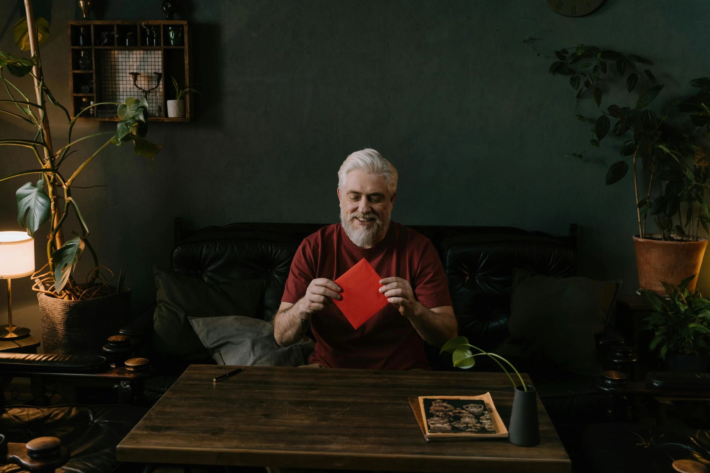 a man sitting at a table holding a red card, pexels contest winner, grandfatherly, square, gif, at home