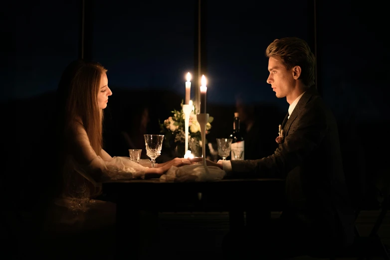 a man and a woman sitting at a table with candles, by Alice Mason, pexels contest winner, romanticism, handsome girl, celebration, ignant, single light
