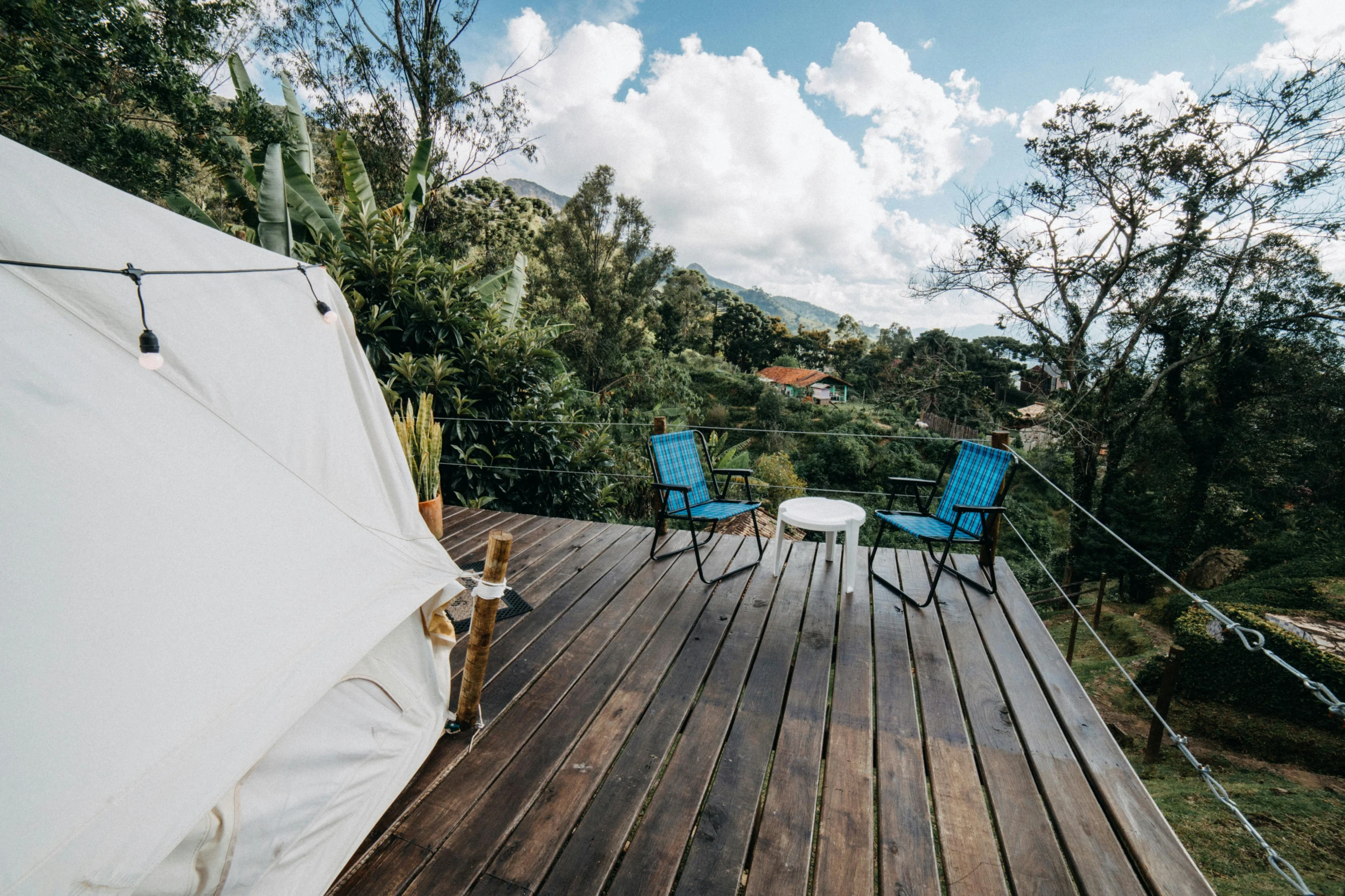 a white tent sitting on top of a wooden deck, unsplash, colombia, hillside, glamping, fullbody view