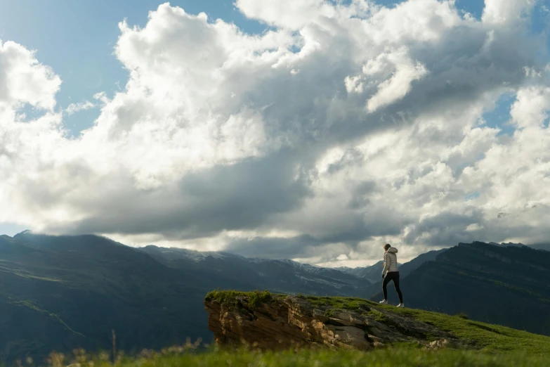 a man standing on top of a lush green hillside, by Peter Churcher, pexels contest winner, girl clouds, standing on boulder, whistler, full body profile